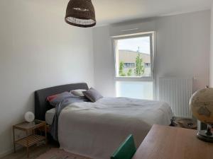 a bedroom with a bed and a window and a table at Maison des mésanges in Colmar