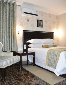 a hotel room with a bed and a chair at Annavilla7 Lilongwe Aparthotel in Lilongwe