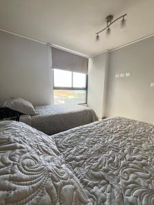 een slaapkamer met 2 bedden en een raam bij Edif Roble in Antofagasta
