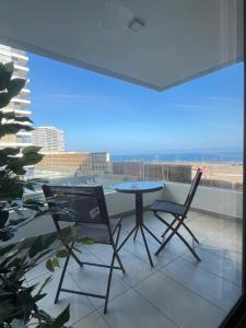 een tafel en stoelen op een balkon met uitzicht op de oceaan bij Edif Roble in Antofagasta