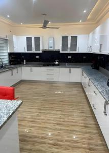 a large kitchen with white cabinets and wooden floors at Emerald Crest in Tamale