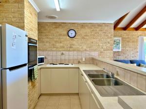 a kitchen with a sink and a clock on the wall at Cliffs Unit 1 - KalbarriWA in Kalbarri