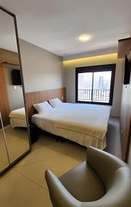 um quarto com uma cama, uma cadeira e uma janela em Lar no Bueno/ Apto. de Luxo 2 quartos em Goiânia