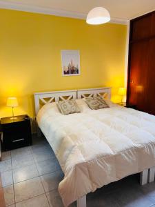 ein Schlafzimmer mit einem weißen Bett und einer gelben Wand in der Unterkunft Depto. Magali en Zona Centro Para 4 Terraza Parrilla in Santiago del Estero
