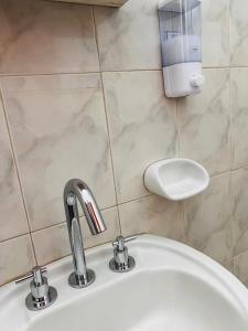 ein weißes Waschbecken mit einem Seifenspender an der Wand in der Unterkunft Depto. Magali en Zona Centro Para 4 Terraza Parrilla in Santiago del Estero