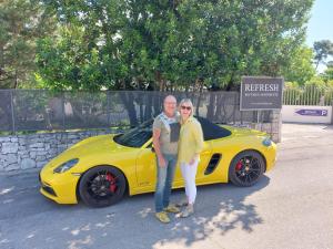 a man and a woman standing in front of a yellow car at Boutique Apartments Refresh in Vodice