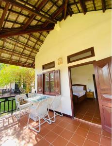 eine Terrasse mit einem Tisch, Stühlen und einem Bett in der Unterkunft Jaguar House Resort Muine in Mui Ne