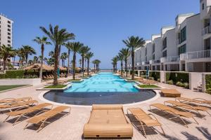a swimming pool with lounge chairs and palm trees at Sapphire Condominiums #806 in South Padre Island