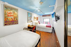 Cette chambre comprend deux lits et une affiche de cinéma. dans l'établissement Chelsea Pines Inn, à New York