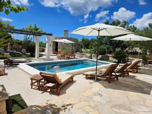 a swimming pool with chairs and an umbrella at Villa Žurnata in Bogomolje