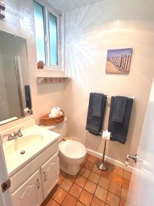 uma casa de banho com um WC branco e um lavatório. em Oceanview Retreat - Steps to the Beach and 2 Pools em Oceanside
