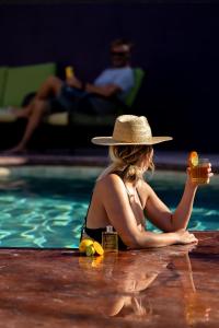 una mujer con sombrero sosteniendo una bebida en una piscina en Hotel Hondo en Los Barriles