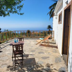 un patio con mesa, sillas y el océano en Auténtica Casa Rústica Canaria en Puntagorda