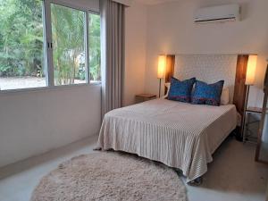Un dormitorio con una cama con almohadas azules y una ventana en La casa del arbol, en Nosara