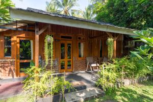 une maison en bois avec une terrasse couverte dans l'établissement Tahlia's Villa, à Sorongjukung