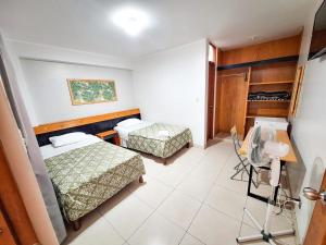 卡马纳Hostal Montecarlo的客房设有两张床、一张书桌和风扇