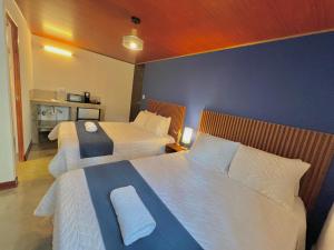Habitación de hotel con 2 camas con sábanas blancas en Hotel Citadin Z10, en Guatemala