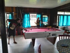 two people playing pool in a room with a pool table at Hostel e Pousada Araquari in Paraty