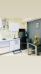 a kitchen with white cabinets and a table and a black refrigerator at Azure Urban Residences in Manila
