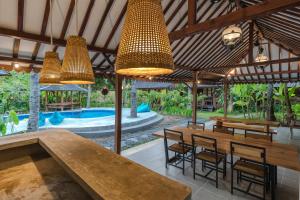 una zona pranzo all'aperto con tavoli, sedie e piscina di Tahlia's Villa a Sorongjukung