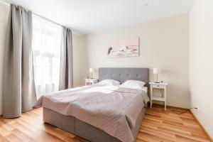 a white bedroom with a bed and a window at Liidia Apartments in Haapsalu