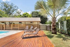 a deck with chairs and a palm tree next to a house at Espaço Barão - Área de Lazer in Araraquara