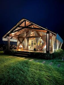 a large wooden house at night with a green lawn at Vicença Glamping in Praia Grande