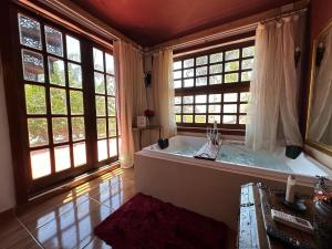 uma grande casa de banho com banheira e janelas em Divina Cabana - Lago Corumbá IV - Alexânia em Alexânia