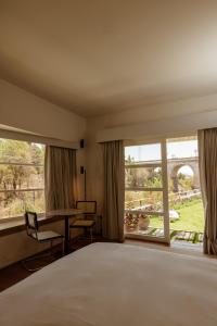 1 dormitorio con cama, escritorio y ventana grande en La Posada del Puente, en Arequipa