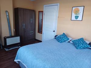 1 dormitorio con 1 cama azul y 2 almohadas azules en Casa Celeste, en Punta Arenas
