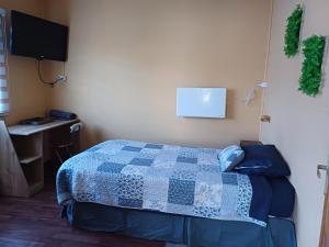 um quarto com uma cama, uma secretária e uma televisão em Casa Celeste em Punta Arenas