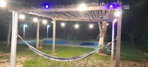 a hammock under a pergola in a yard at night at Recanto agape chalés e cabana in Rosas