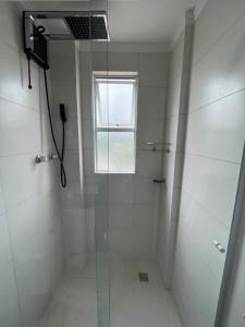 a bathroom with a glass shower with a window at Quarto de Casal em Blumenau in Blumenau +3 photos