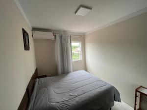 a small bedroom with a bed and a window at Quarto de Casal em Blumenau in Blumenau