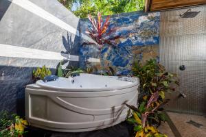 baño con bañera blanca y planta en Ocho Artisan Bungalows, en Tamarindo