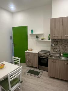 a kitchen with a green door and a table with chairs at "Il Gelso" in Villa G reco in Tindari