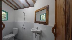 ein Badezimmer mit einem Waschbecken, einem WC und einem Spiegel in der Unterkunft Hakiki Inn Bungalows in Tetebatu