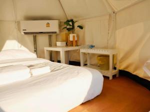 a bedroom with a bed and two tables in a tent at Muengtaboon Camping Park in Thung Yai