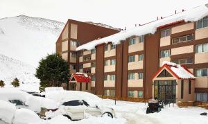 a snow covered building with cars parked in front of it at Rodas - Las Leñas in Las Lenas