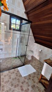 a bathroom with a toilet and a glass shower at Villa das Palmeiras Chalés & Camping in São Bento do Sapucaí
