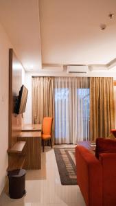 een woonkamer met een bank, een tafel en een televisie bij Lorin Dwangsa Solo Hotel in Solo