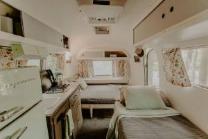 an rv bedroom with two beds and a kitchen at Streamside ShinyTiny Airstream in the Smokies in Cosby