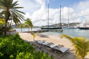 a group of lounge chairs on a beach with a cruise ship at South Point Antigua Ocean Suites in English Harbour Town