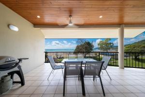 a dining room with a table and chairs on a patio at Whitsunday Beachfront Apartment on Coral Esplanade in Cannonvale +13 photos