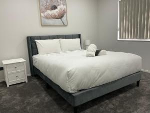 a bedroom with a large bed with white sheets at Holiday Home or Short term Rental in Papatoetoe in Auckland
