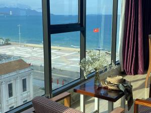 um quarto com uma mesa e vista para o oceano em Happy Light Hotel Nha Trang em Nha Trang