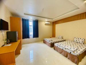 a hotel room with two beds and a television at Sunny 1 Hometel Vinh Long in Vĩnh Long