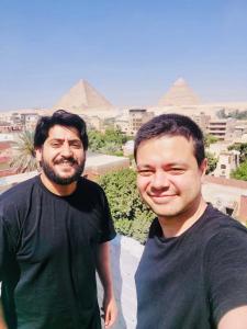 zwei Männer stehen nebeneinander vor Pyramiden in der Unterkunft LOAY PYRAMIDS VIEW in Kairo