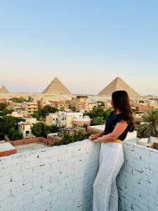 a woman standing on a wall looking at the pyramids at LOAY PYRAMIDS VIEW in Cairo