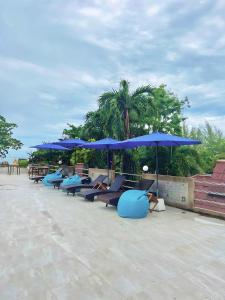 una fila de sillones azules bajo sombrillas en Days Inn by Wyndham Aonang Krabi, en Ao Nang Beach